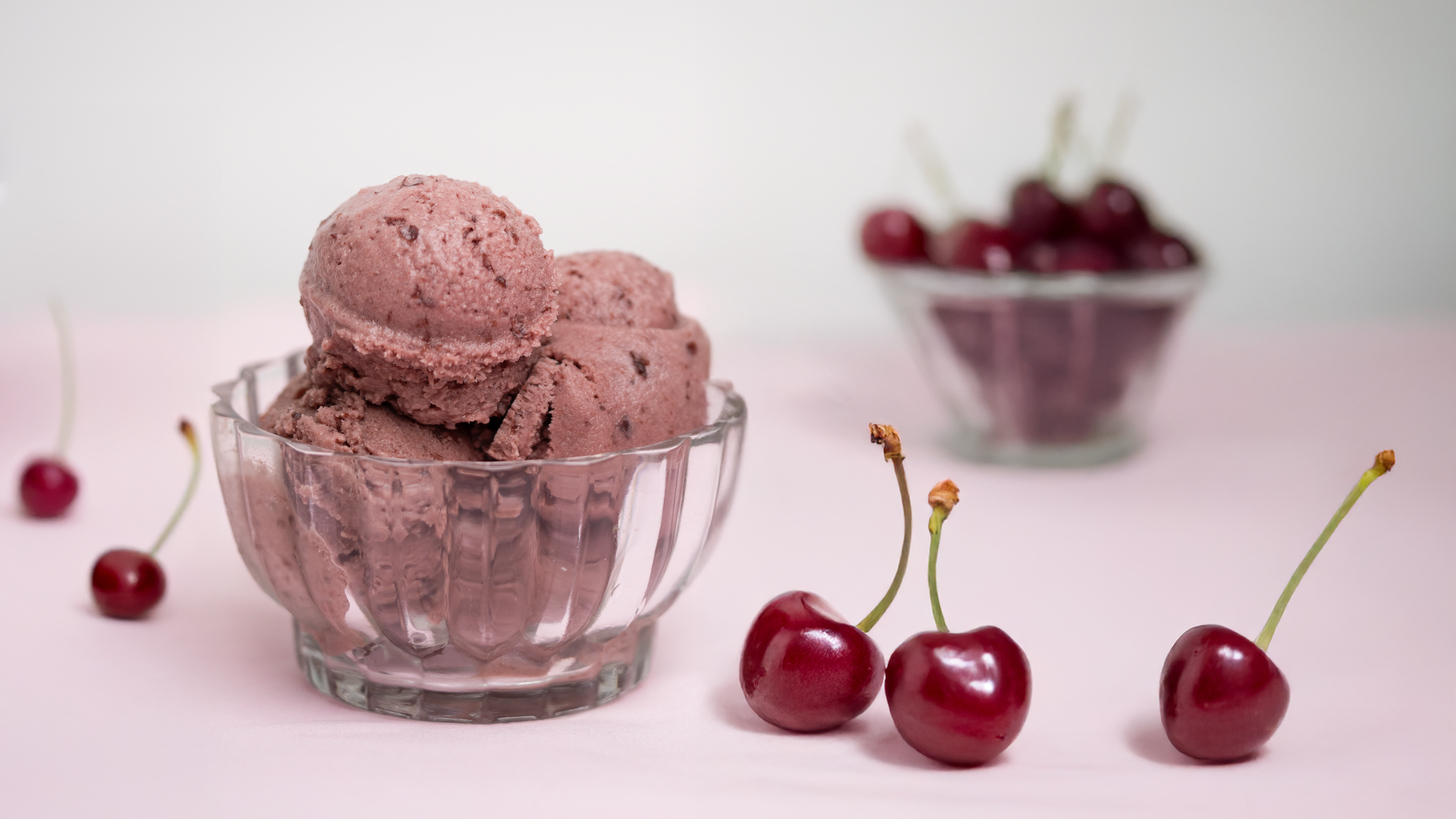 Cherry ice cream in a glass bowl with fresh cherries